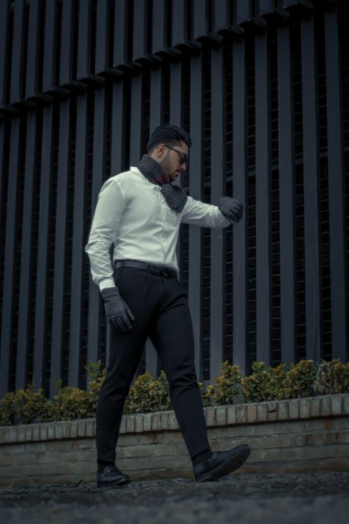 Free Fashionable adult man walking outdoors in winter attire, glancing at his watch. Stock Photo