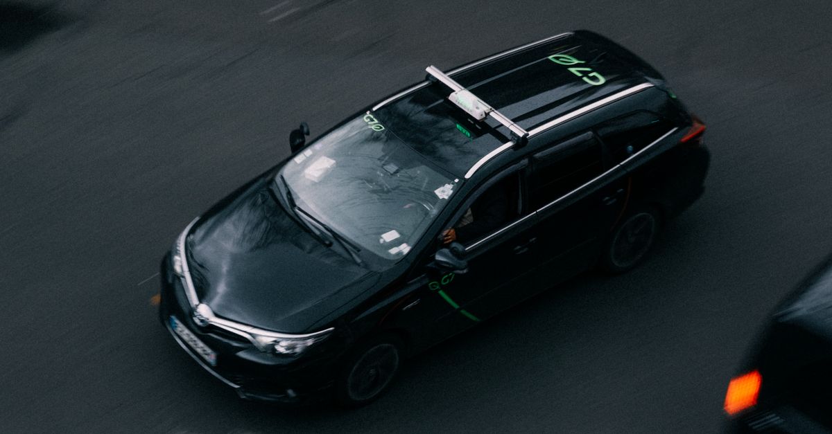 Vue en plongée d'une voiture noire se déplaçant avec un flou de mouvement sur une rue de ville, capturée d'en haut.