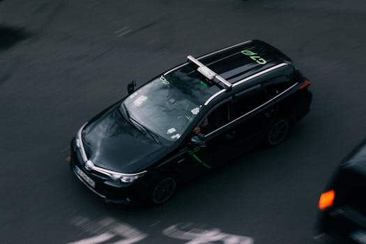 High-angle view of a black car moving with motion blur on a city street, captured from above.