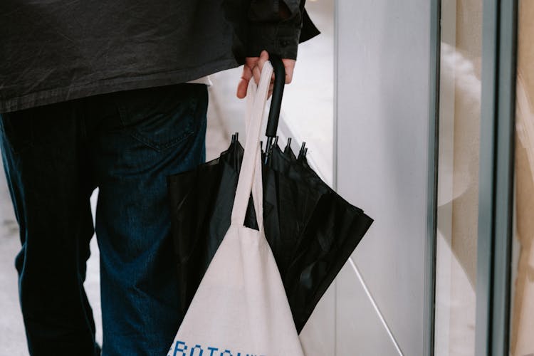 Man Carrying Umbrella And Bag On City Street