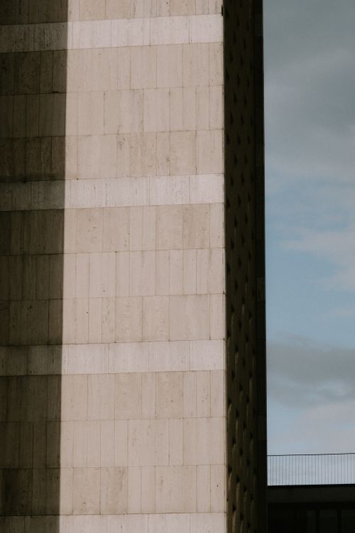 Free Close-up of a modern building with contrasting shadows and a blue sky backdrop. Stock Photo