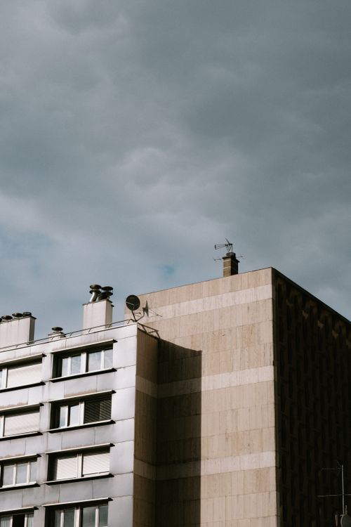 Free Contemporary concrete building with glass panels under a dramatic cloudy sky. Stock Photo