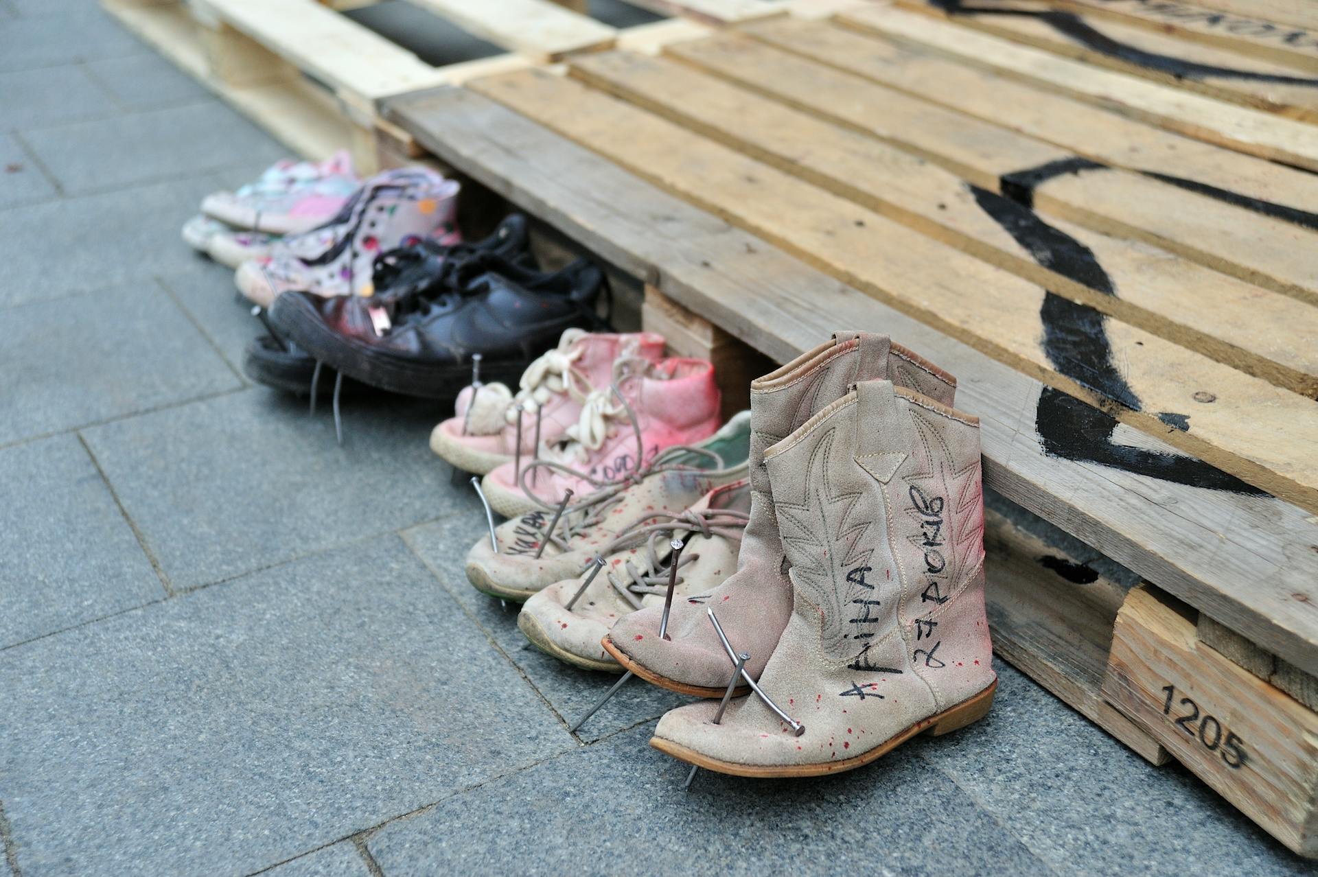 Display of various shoes on a wooden pallet in Lviv, Ukraine, symbolizing memorial.