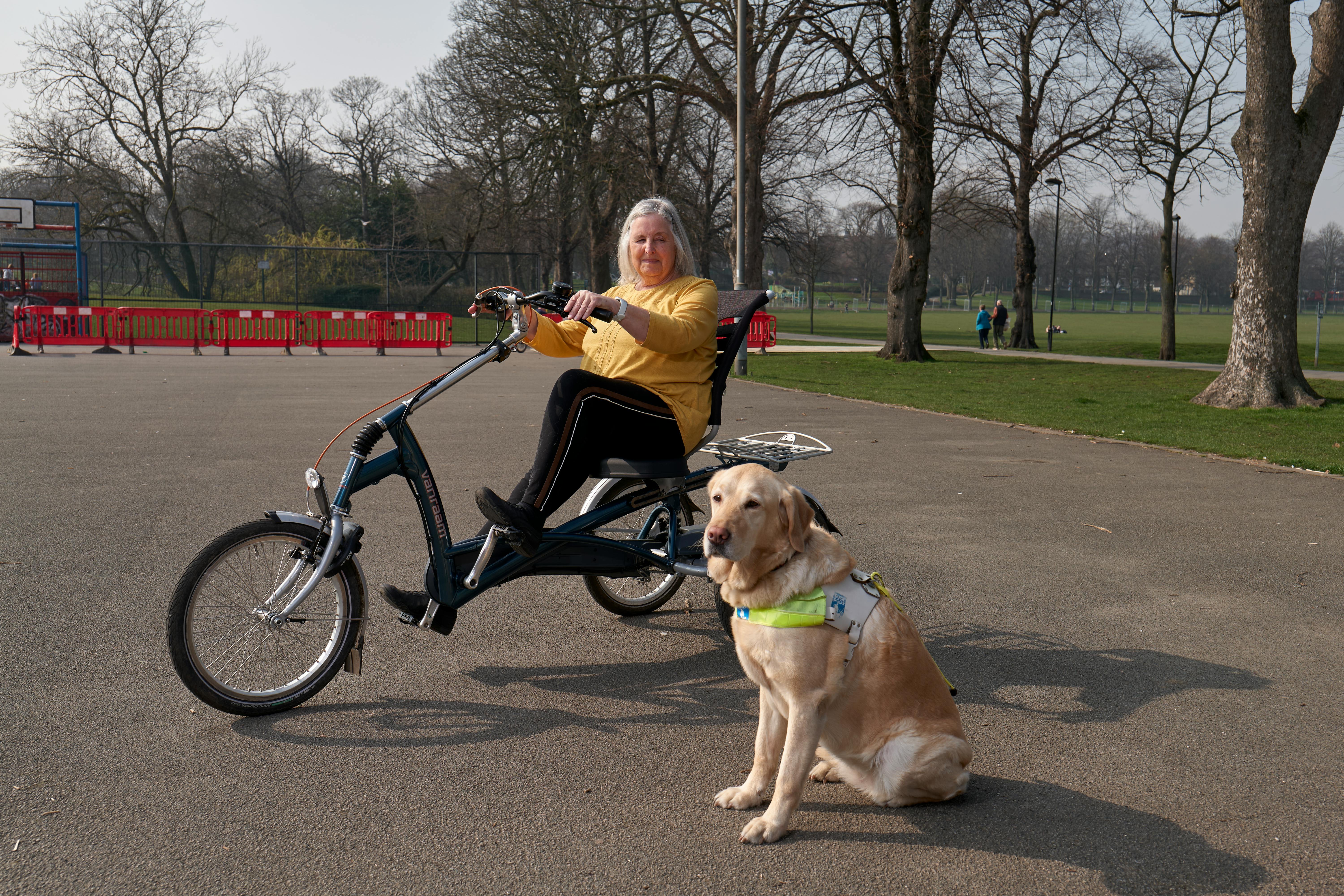 Elderly Woman on a Bike for Disabled People with a Guide Dog