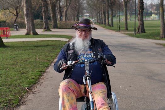 An elderly man with a hat and beard rides a specialized bike in a serene park setting.
