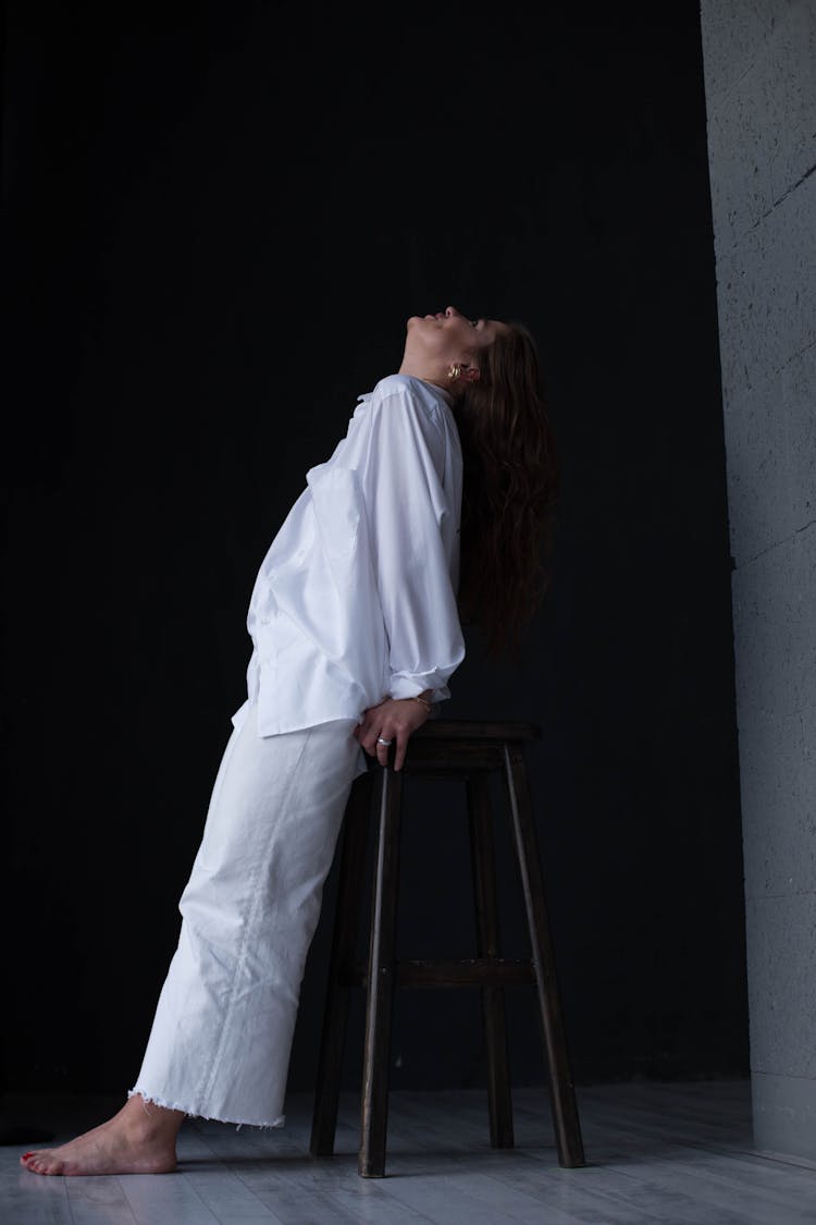 Woman In Loose Clothing Stretching On Stool