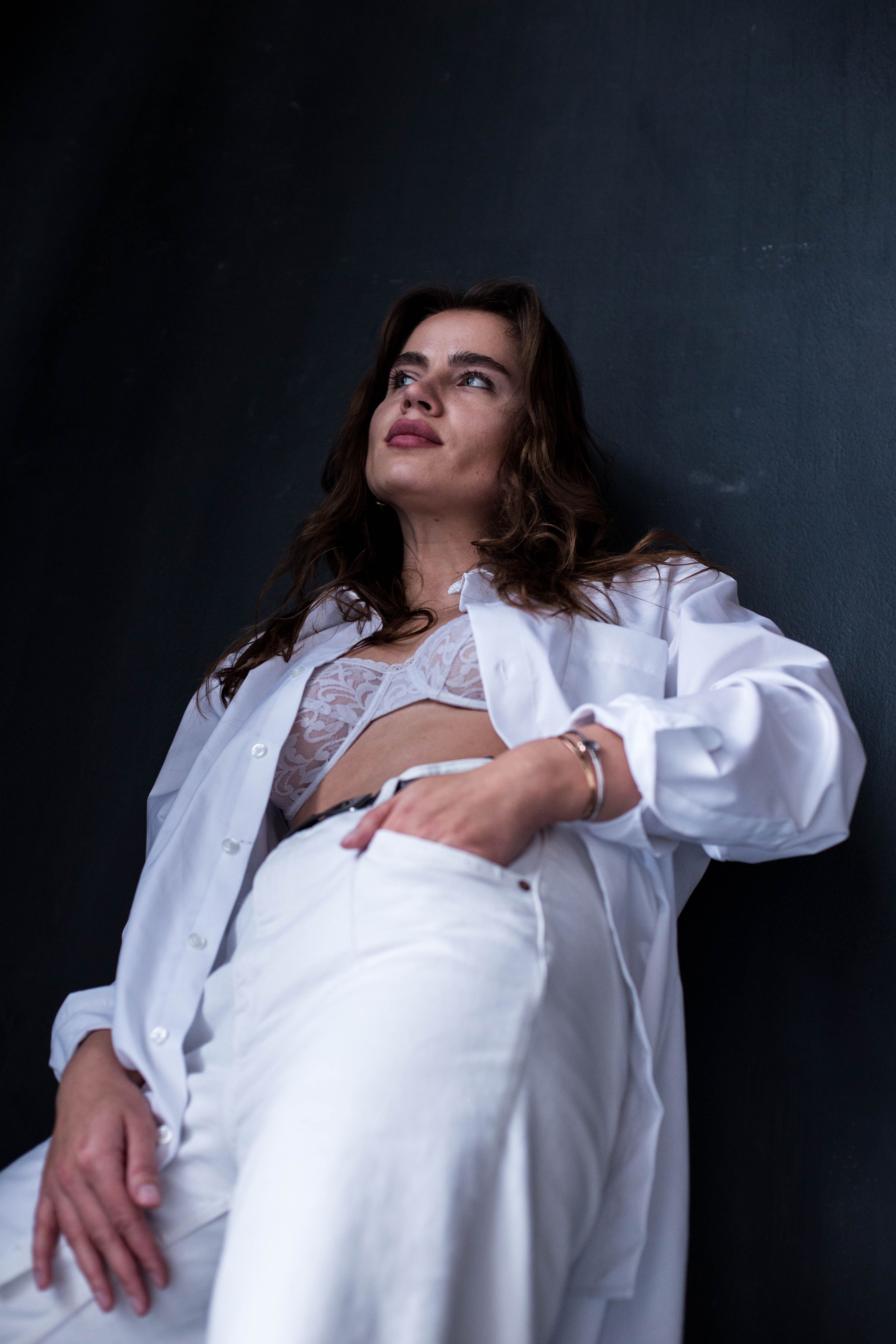 Confident woman in white clothing, posing against a dark background.
