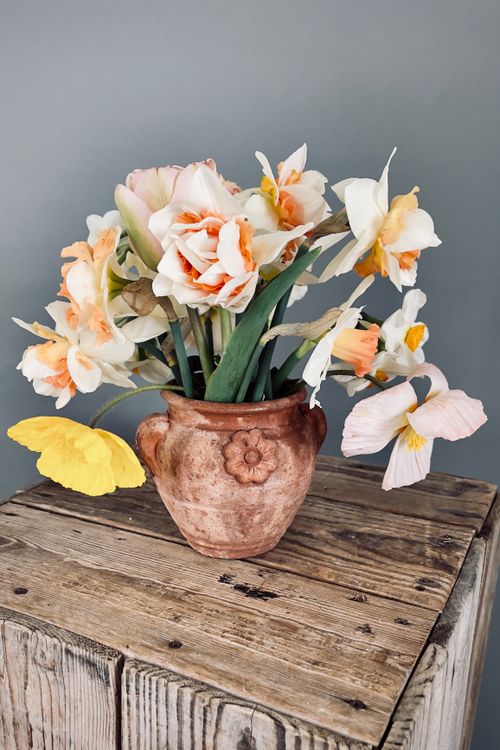 Free A ceramic vase filled with blooming daffodils sits gracefully on a rustic wooden table. Stock Photo