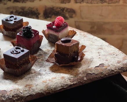Close-up of assorted miniature desserts, highlighting chocolate and fruit garnishes on a rustic table.