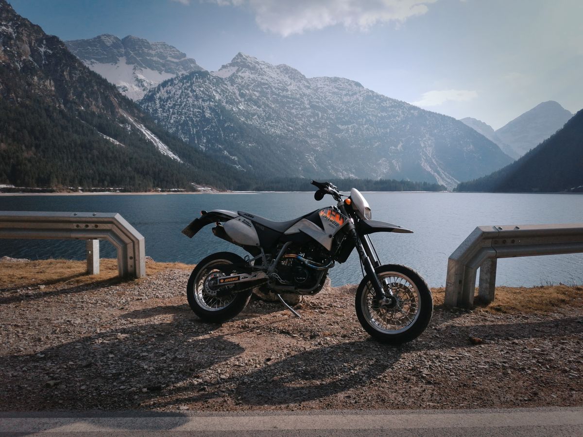 Motocicleta enduro parcata langa un lac alpin din Tirol
