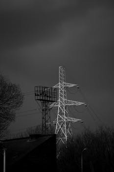 Monochrome image of power lines and industrial structures under a moody sky.