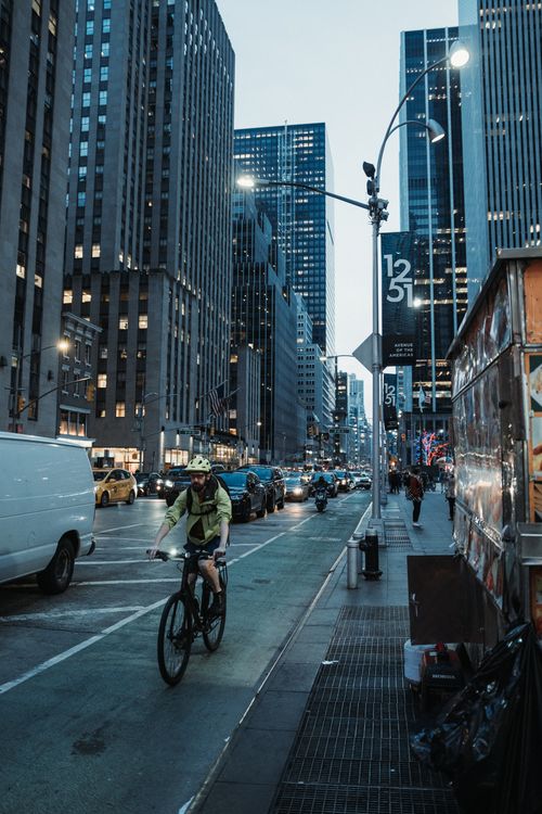 Free Bicyclist riding through the bustling streets of Manhattan during the evening rush hour. Stock Photo