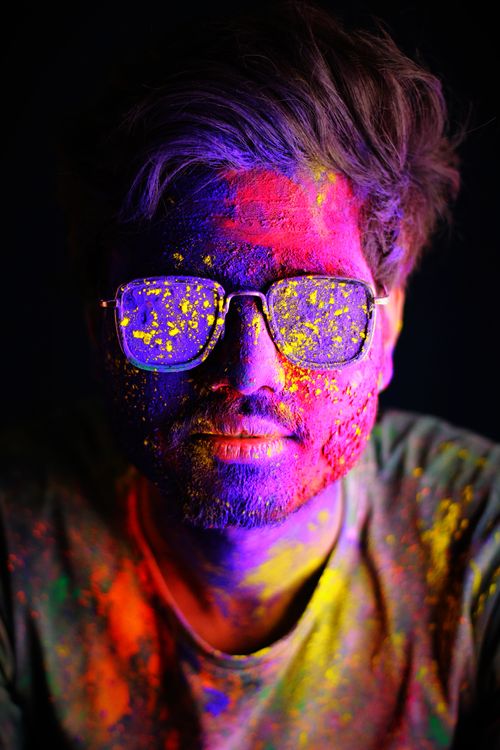 Free A young man celebrates Holi with vivid colors covering his face, highlighting traditional culture. Stock Photo