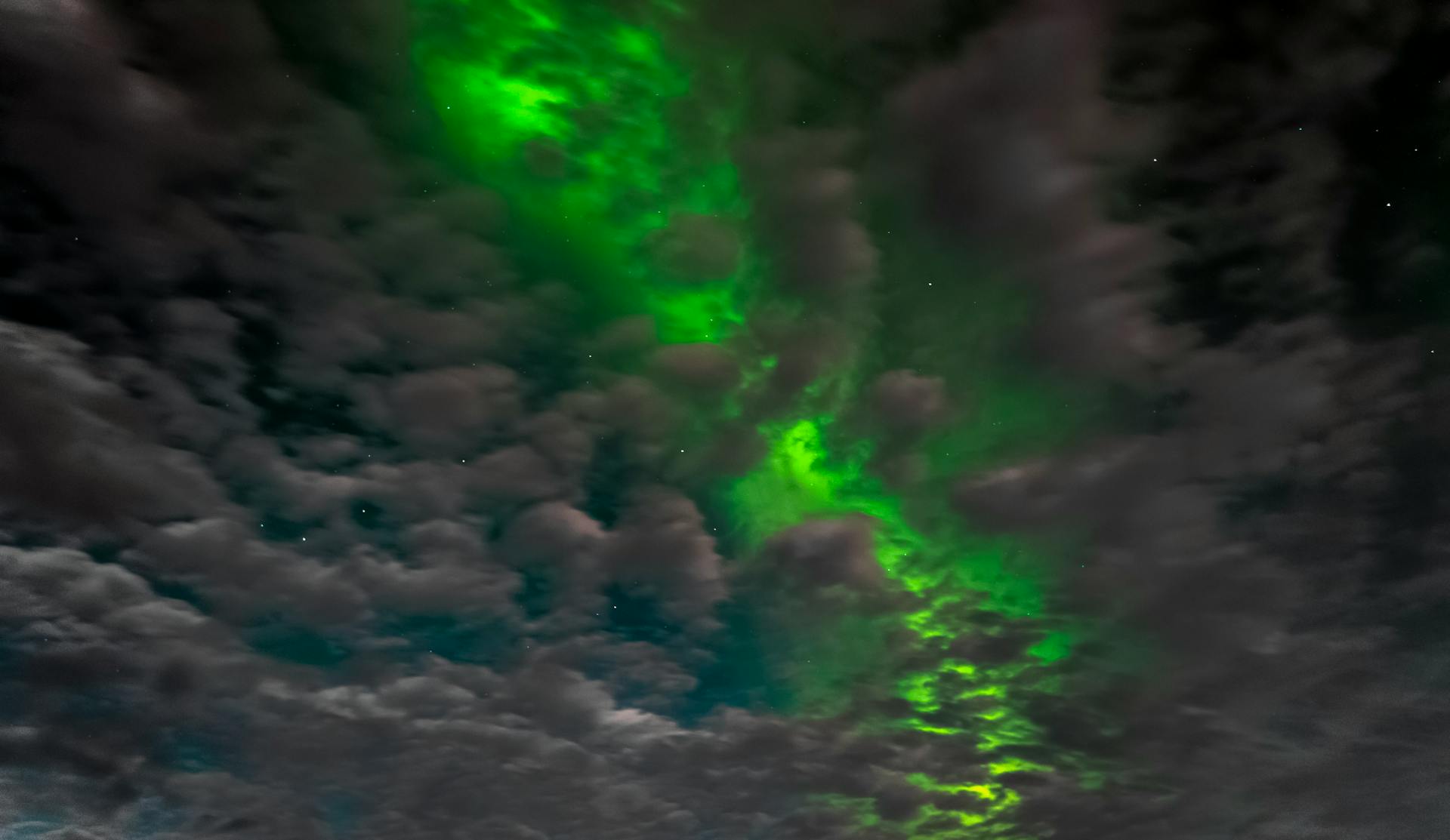 Vivid aurora borealis illuminating the cloudy night sky in Nordland, Norway.