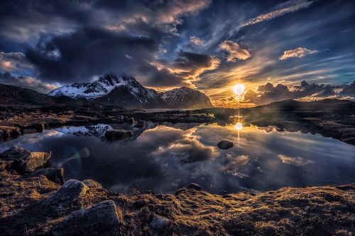 Free Majestic sunset over a tranquil lake in Nordland, Norway with dramatic skies and mountain reflections. Stock Photo