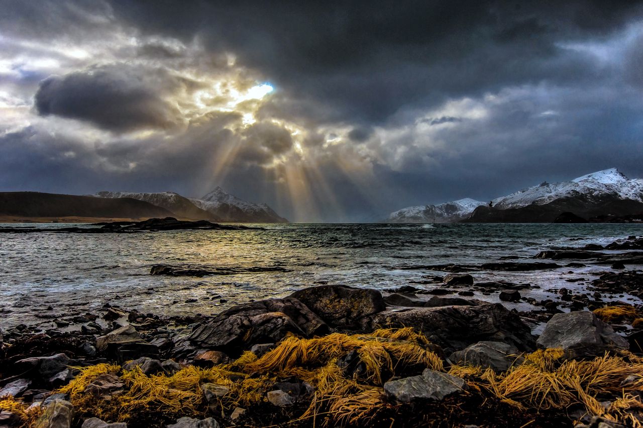 breathtaking view of sunbeams piercing through clouds over a rocky nor