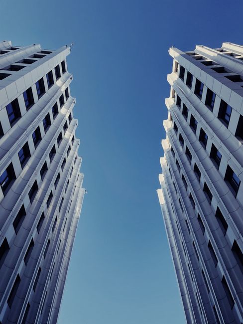 Explore striking modern skyscrapers with a symmetrical design under a clear blue sky.