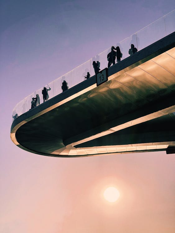 Silhouettes of People Standing on Floating Glass Bridge