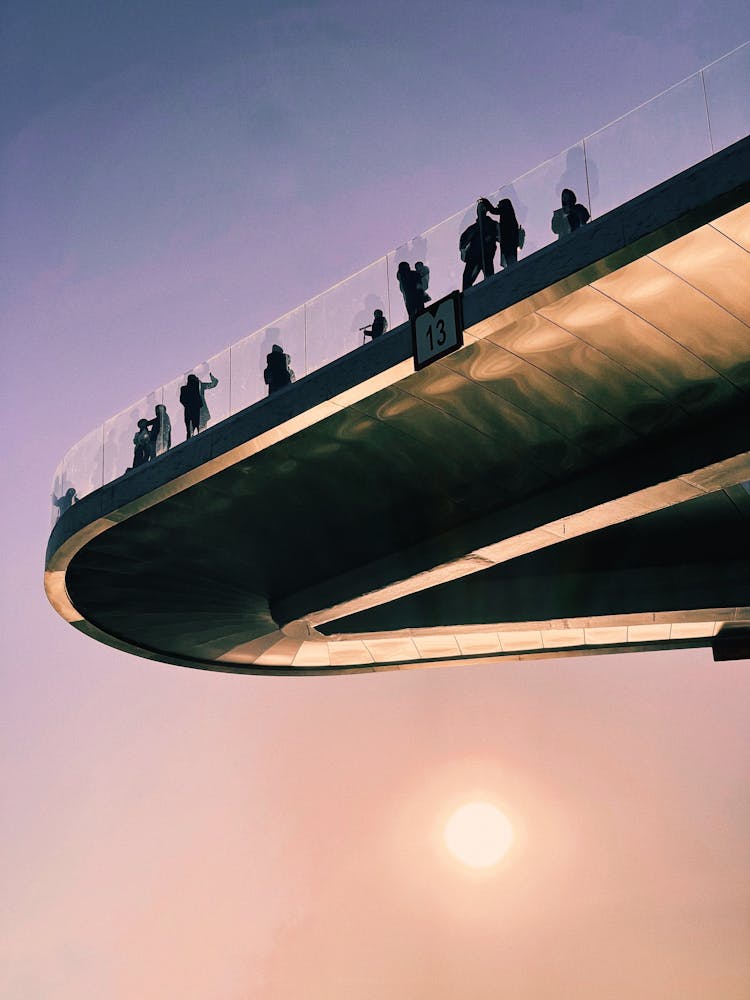Silhouettes Of People Standing On Floating Glass Bridge