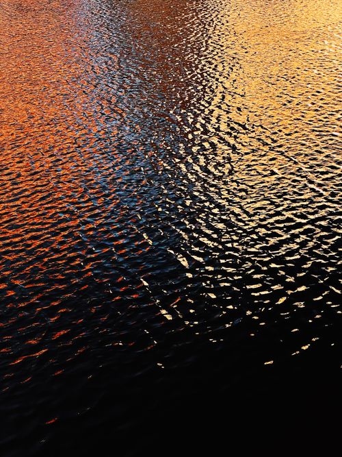 Free Vivid sunset reflections create a mesmerizing pattern on the rippled water surface. Stock Photo