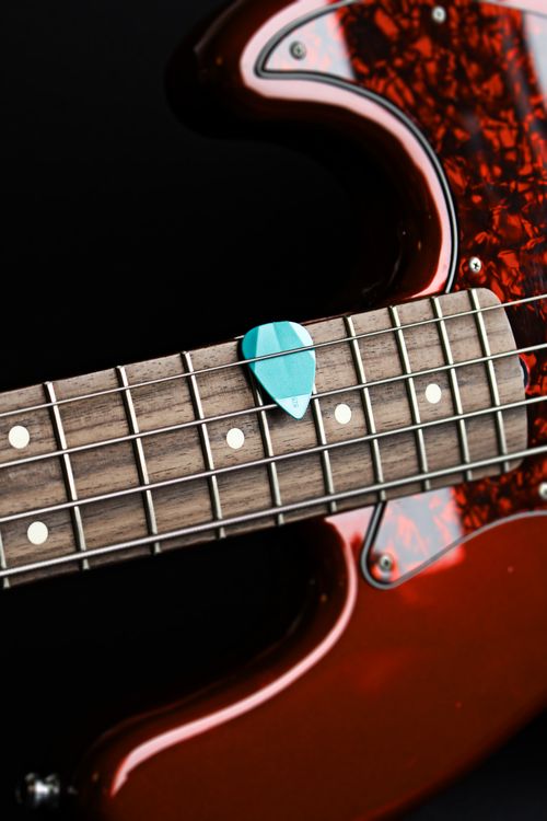 Free Detailed view of a bass guitar neck with a blue guitar pick on its strings. Stock Photo