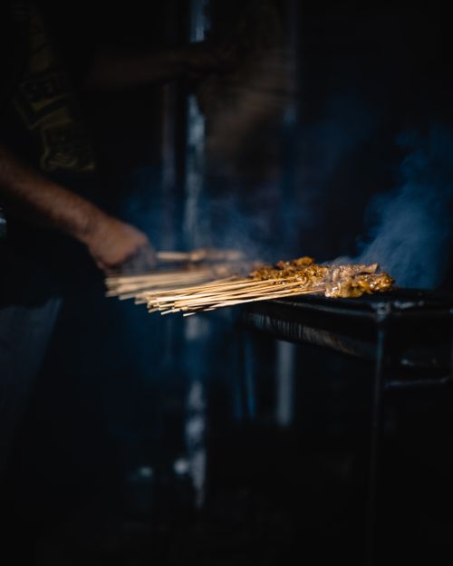 Free Skewers of meat being grilled outdoors with smoky ambiance adding flavor. Stock Photo