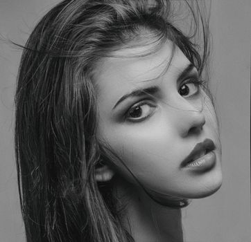 Elegant black and white close-up of a woman with expressive eyes and flowing hair.