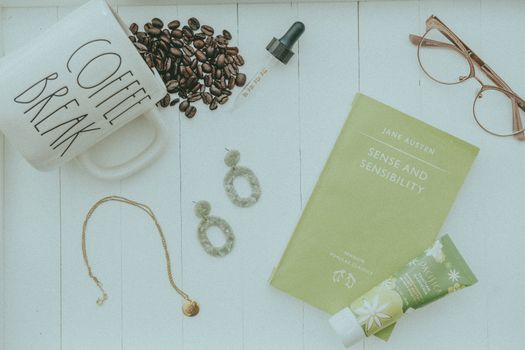 Flat lay of coffee, book, and accessories for a relaxing vibe.