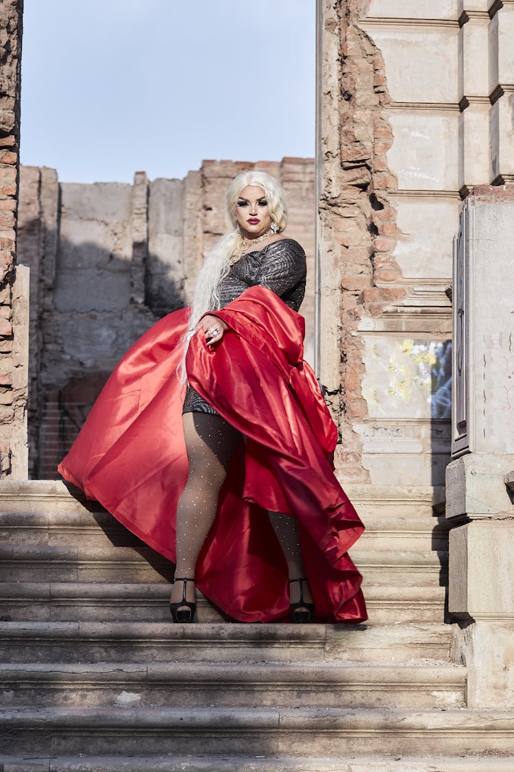 Drag Queen Posing In Red Dress On Stairs Of Castle