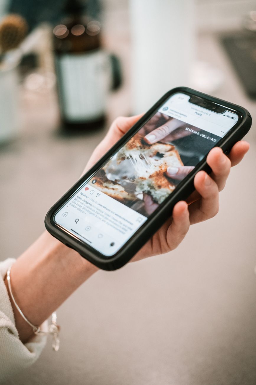 Woman's hand holding smartphone displaying social media content in close-up view.