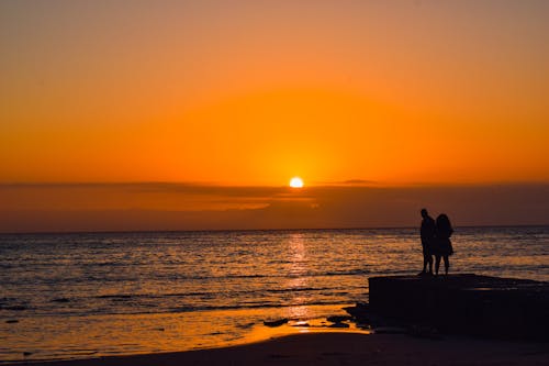 Golden Hour Silhouette of People Standing in Front of Sea