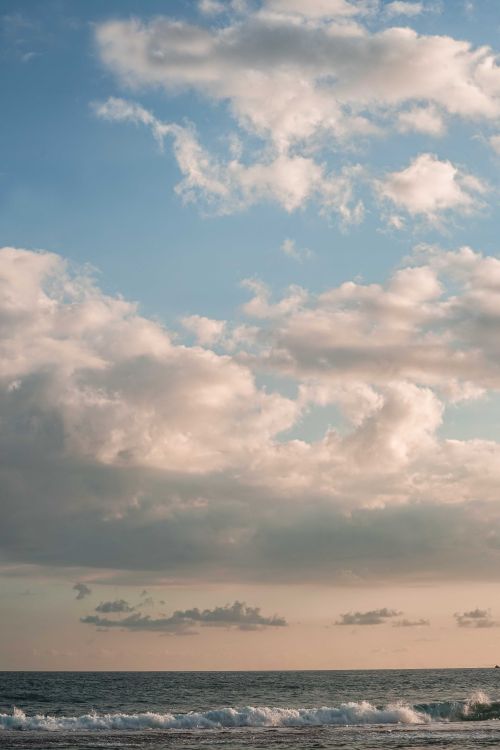 Free Tranquil ocean waves with a dramatic cloudy sky at sunset, perfect for relaxation themes. Stock Photo