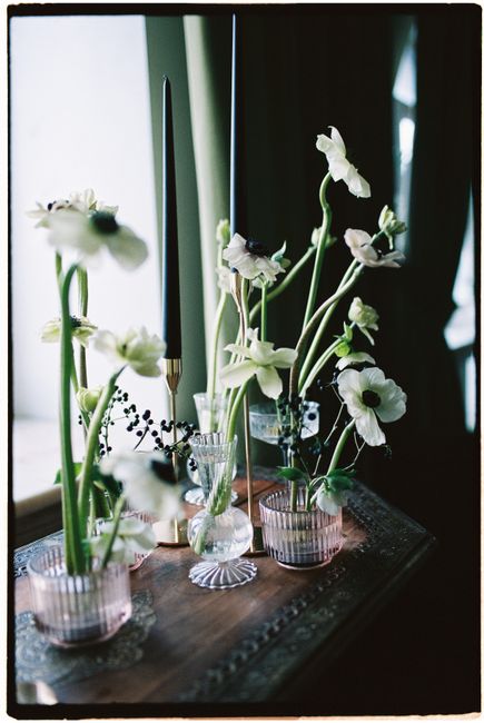 A vintage windowsill adorned with elegant white flowers and candlesticks in a soft, natural light setting.
