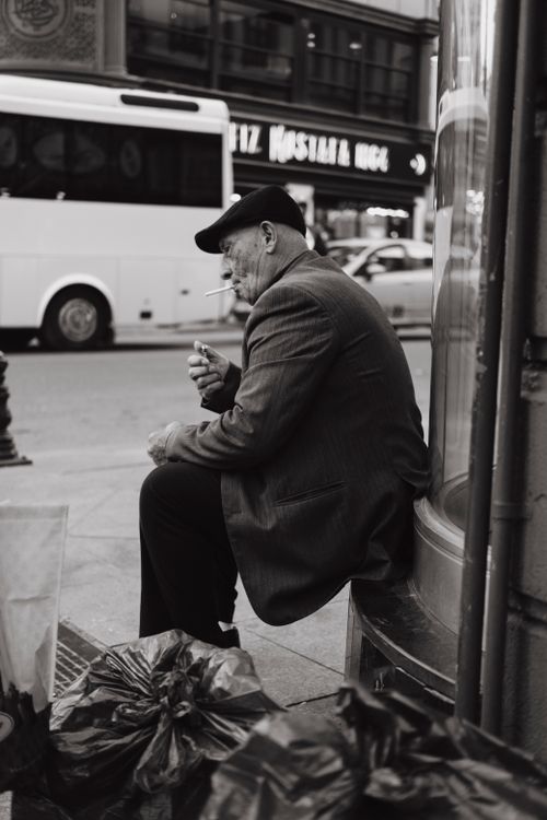 Free Monochrome portrait of an elderly man smoking on a bustling Istanbul sidewalk. Stock Photo