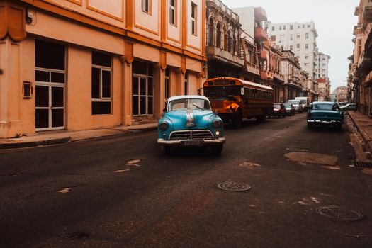 Classic cars drive through a historic city street, capturing a timeless urban scene.