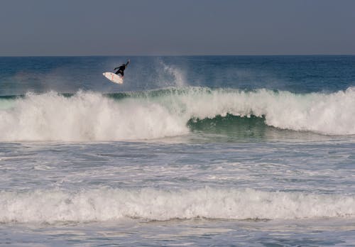 A Person in Black Bodysuit Surfing