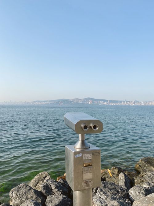 Free Scenic view of the sea with public binoculars and city skyline in the distance. Stock Photo