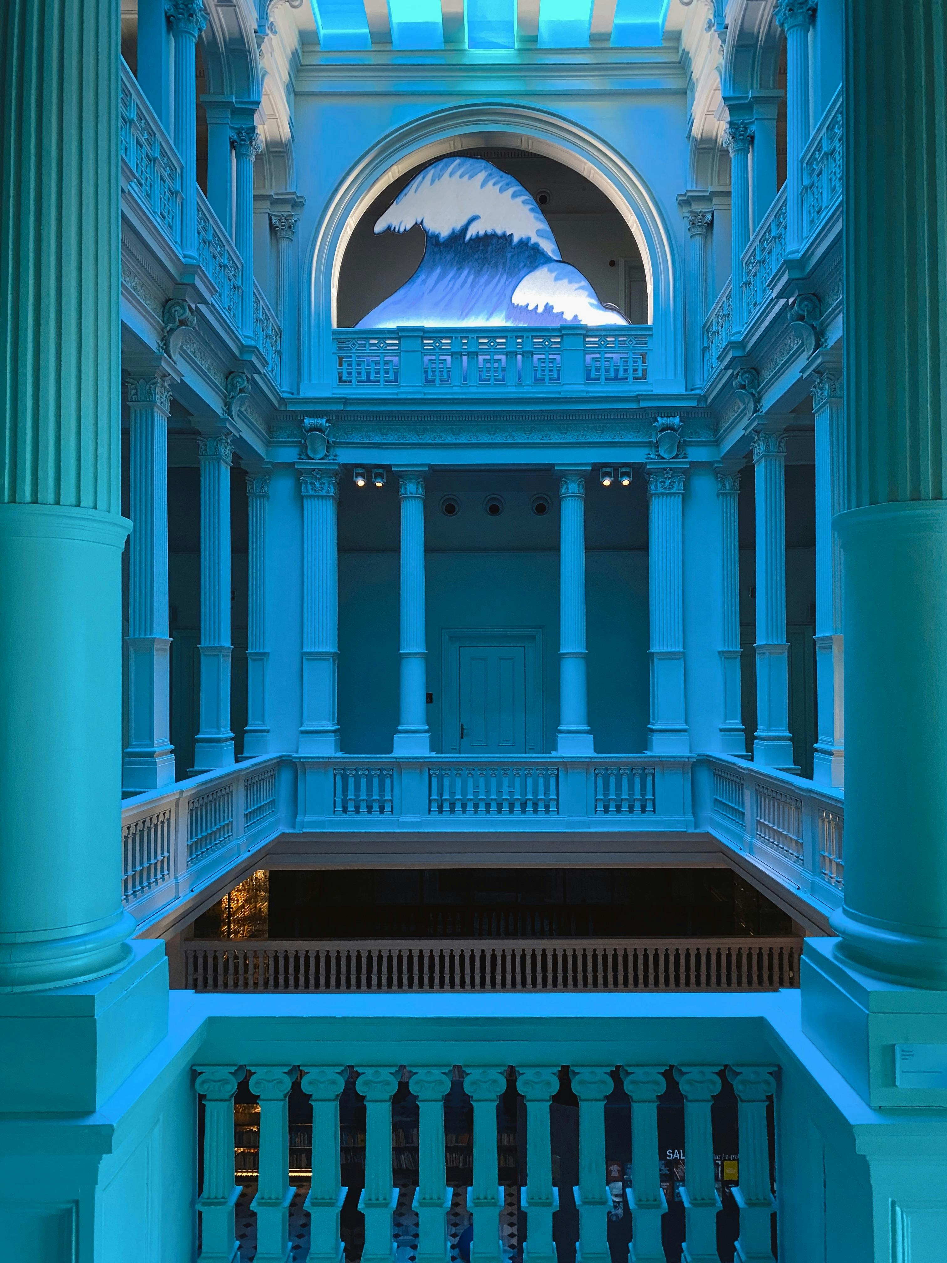 Elegant neoclassical hall featuring a striking wave mural in blue lighting.