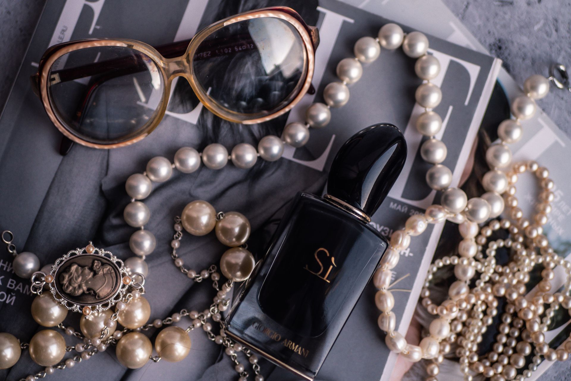 Giorgio Armani Bottle Surrounded by Pearl Accessories and Sunglasses