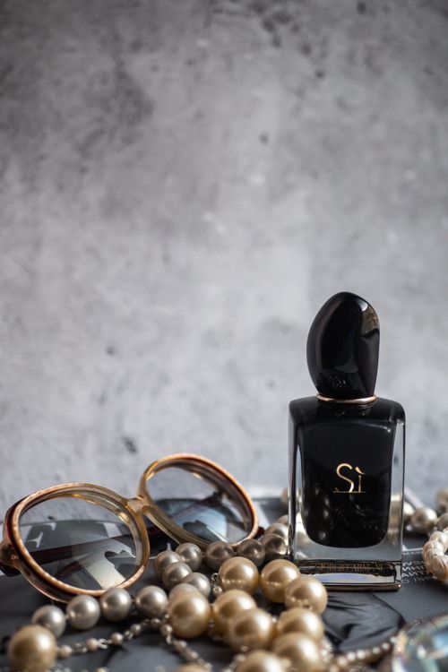 Free Elegant arrangement of luxury perfume, pearls, and sunglasses against a textured background. Stock Photo