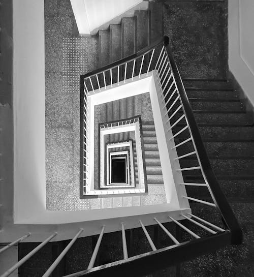 Grayscale Photo of Staircase With Metal Railings