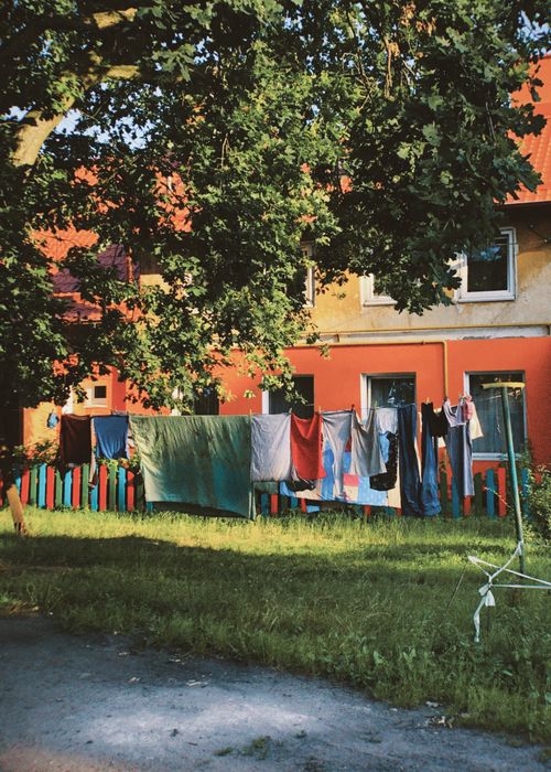 Free Vibrant clothes drying on a line outside a colorful residential building in a sunny urban environment. Stock Photo