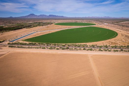 Aerial photograph of lush green circular fields amidst the arid landscape near Stanfield, Arizona.