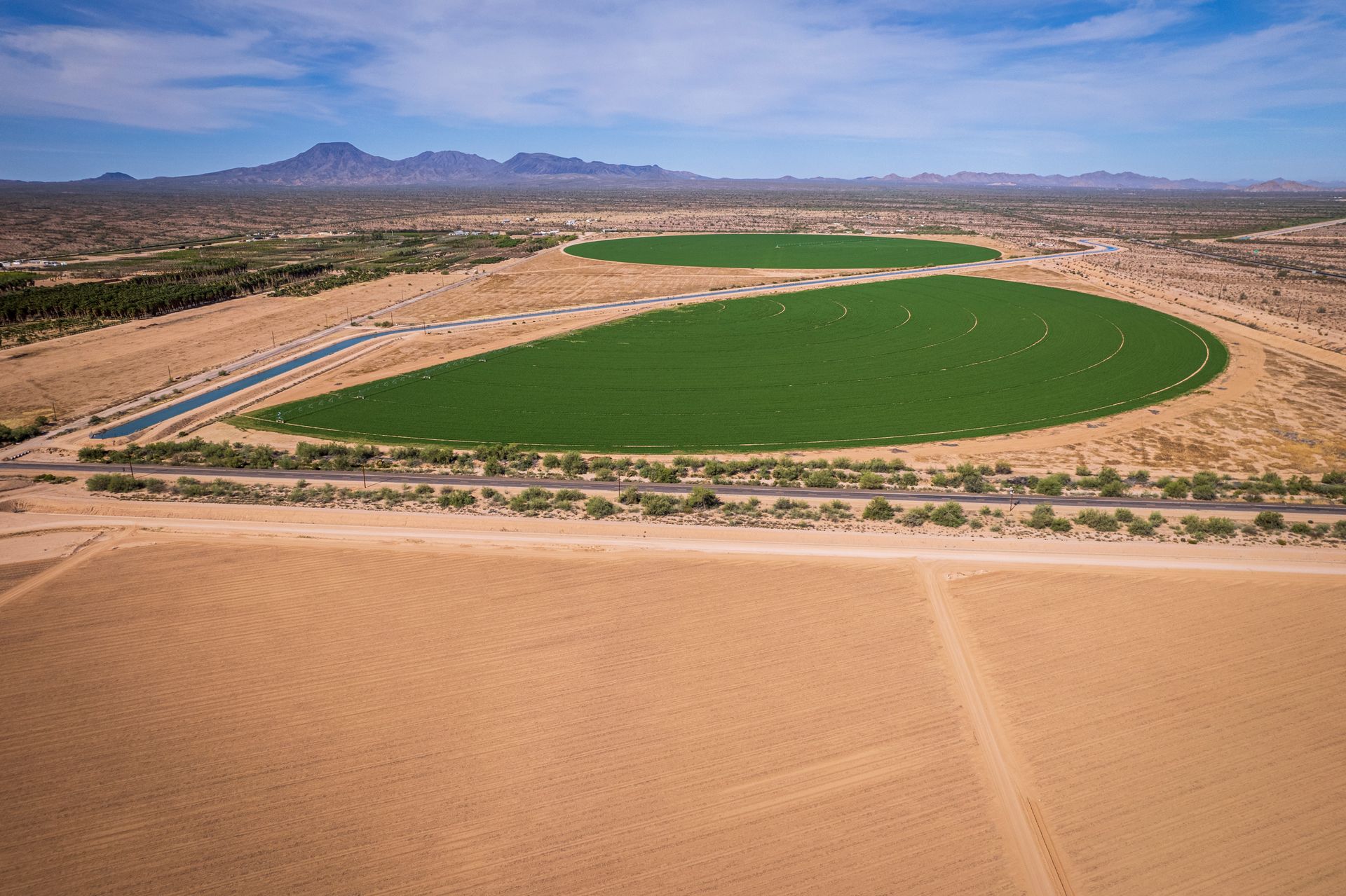 Aerial photograph of lush green circular fields amidst the arid landscape near Stanfield, Arizona.