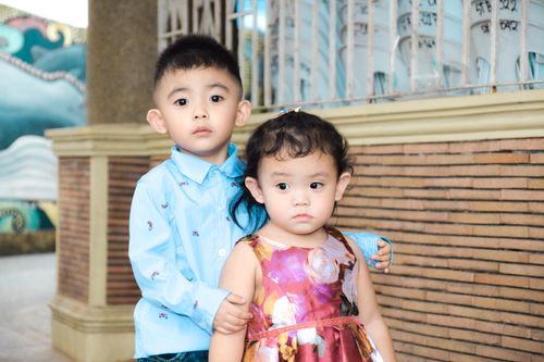 Free Two cute siblings in colorful outfits posing outdoors, showing a close bond and cheerful expressions. Stock Photo