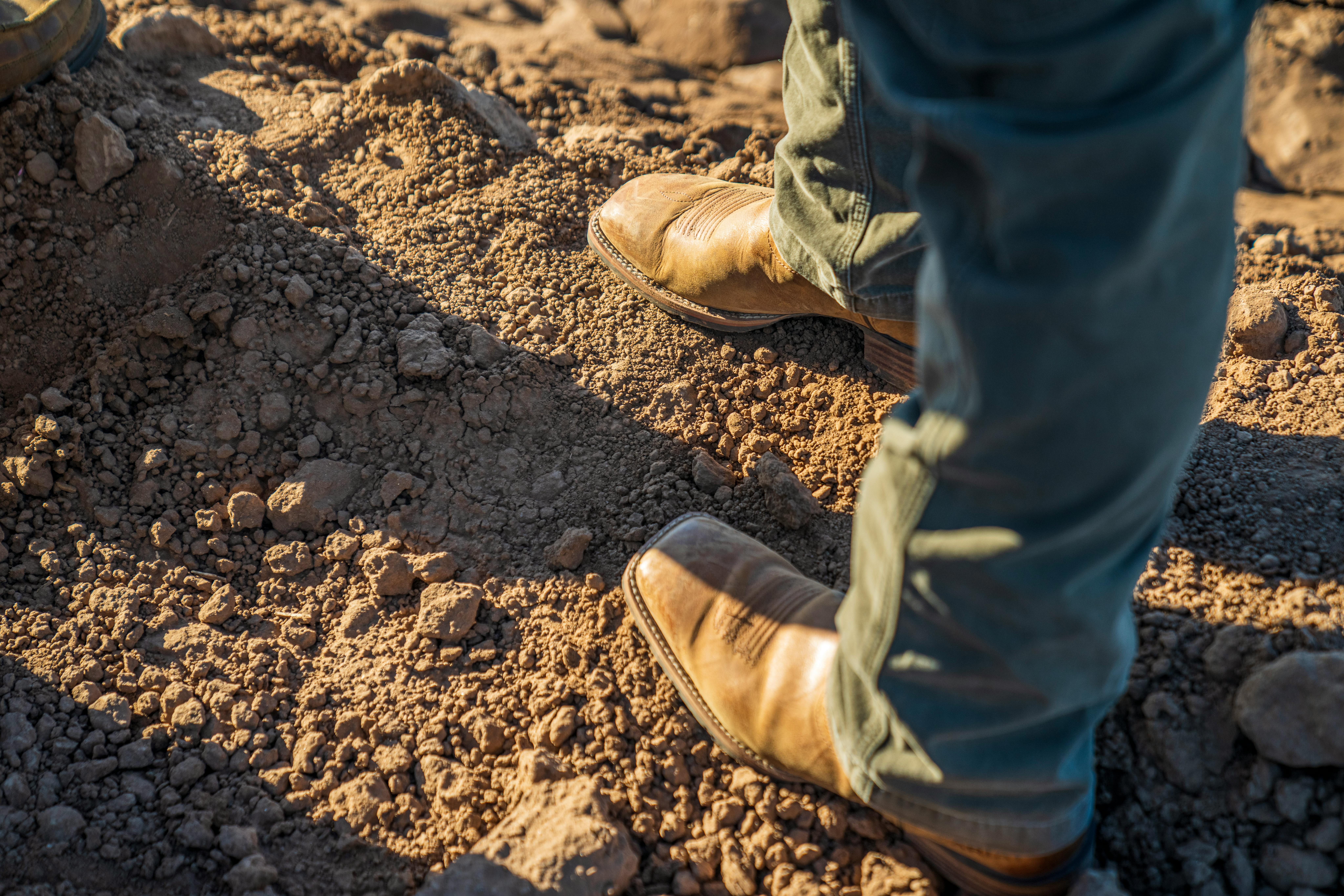 Brown leather boots standing on rocky ground, symbolizing rugged adventure.