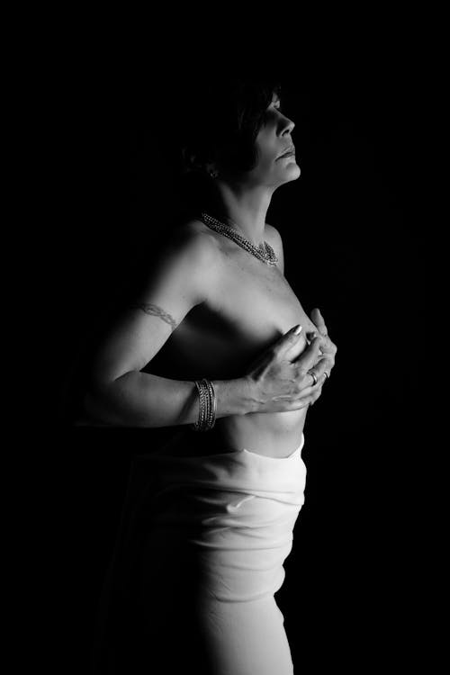 A Shirtless Woman Covering Her Chest while Looking Afar