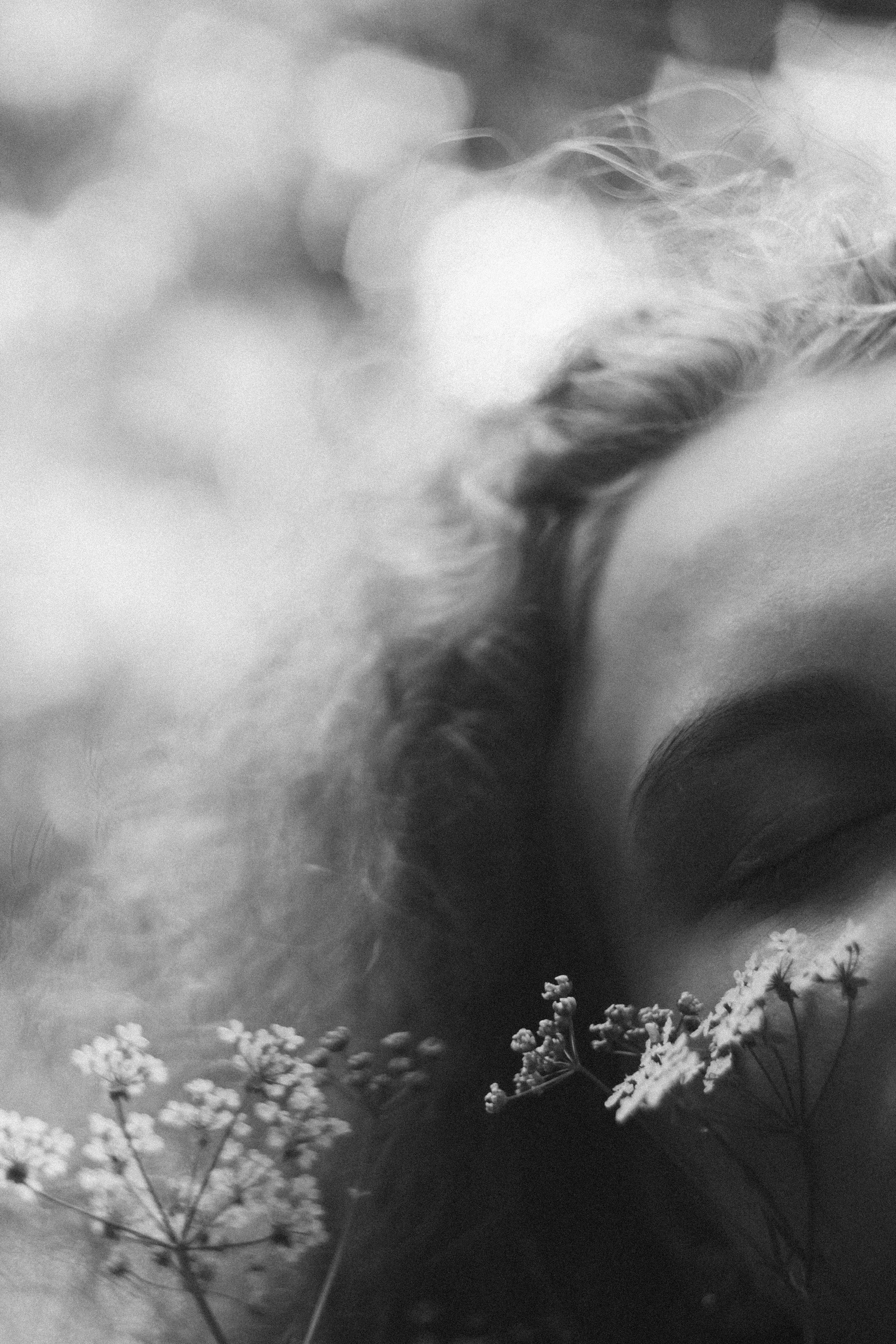 A gentle black and white portrait of a woman with curly hair and flowers.