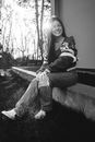 Woman in Black and White Jacket and Blue Denim Jeans Sitting on Concrete Bench