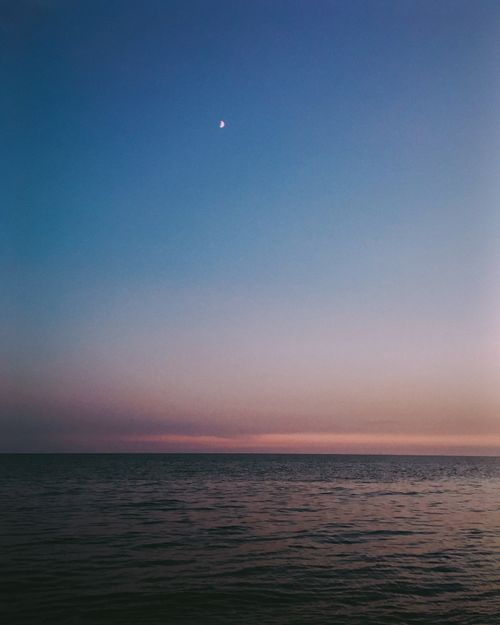 Free Peaceful ocean scene at twilight with moon in blue and pink sky. Stock Photo